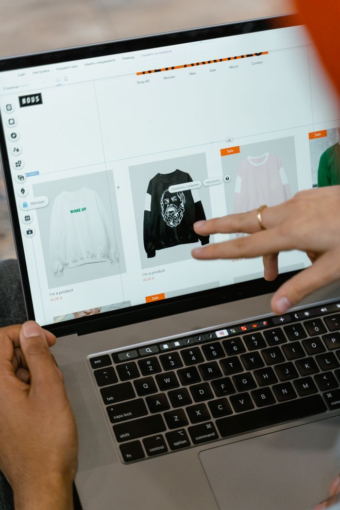 A close-up view of hands using a laptop indoors while browsing a shopping website on the screen.